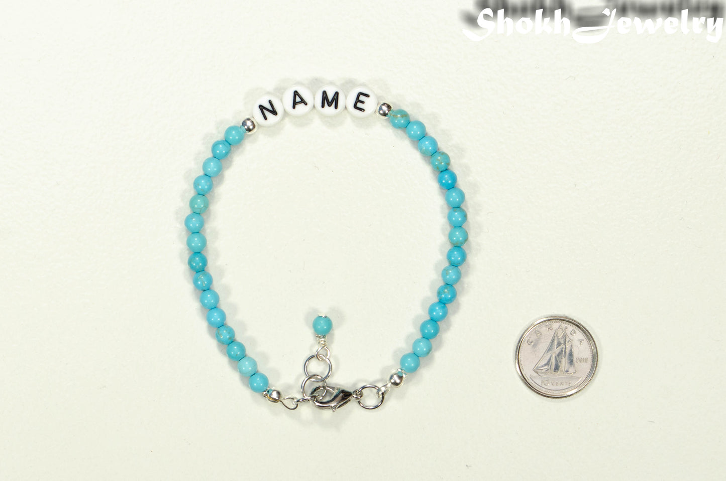 Personalized Turquoise Howlite Name Bracelet with Clasp beside a dime.