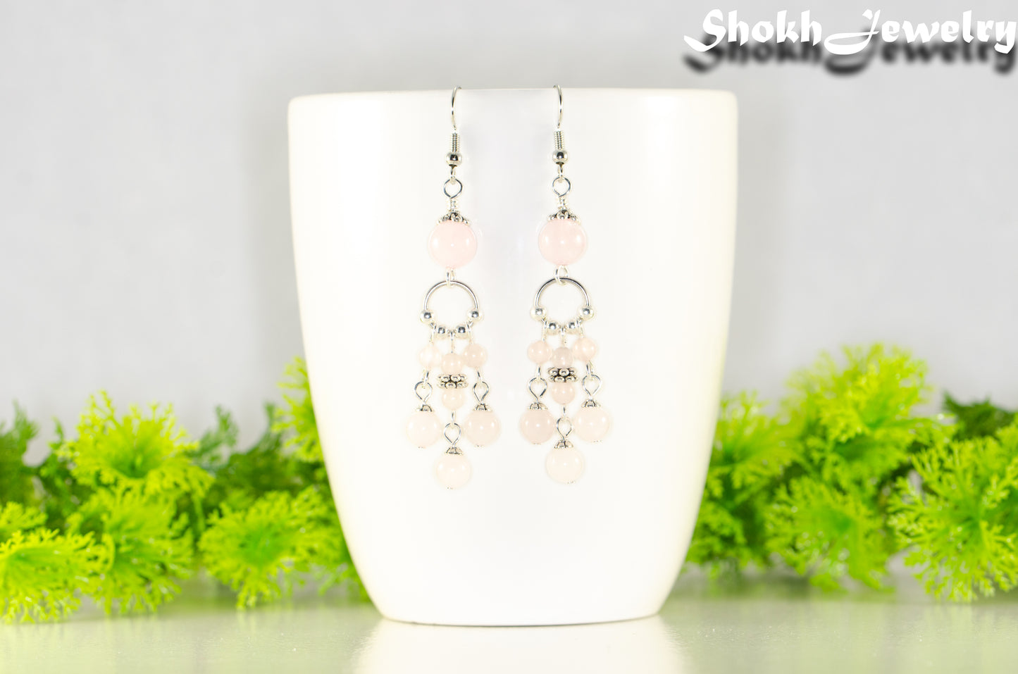 Statement Rose Quartz Chandelier Earrings displayed on a white coffee mug.