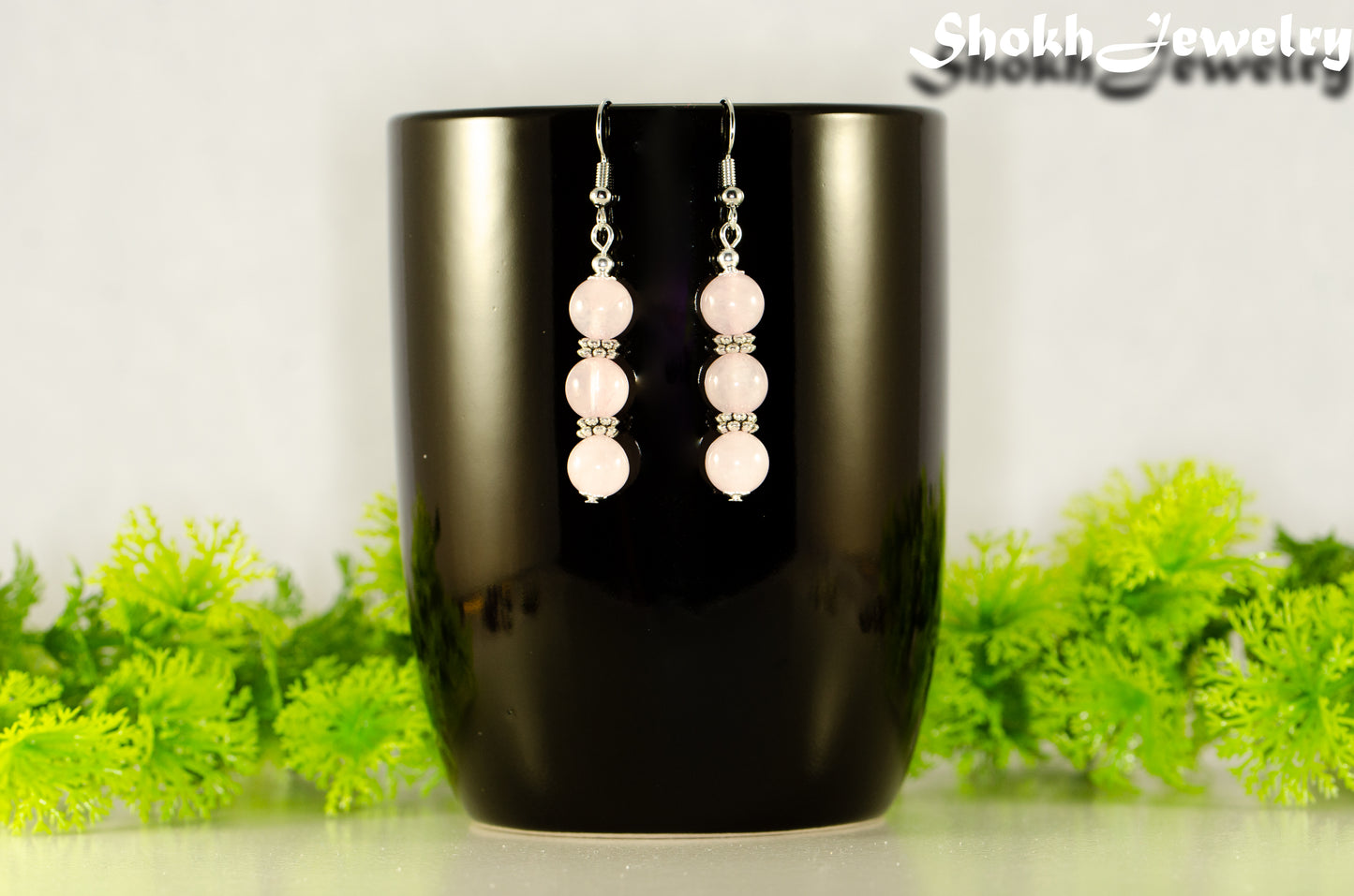 Natural Rose Quartz Beaded Bar Earrings displayed on a coffee mug.