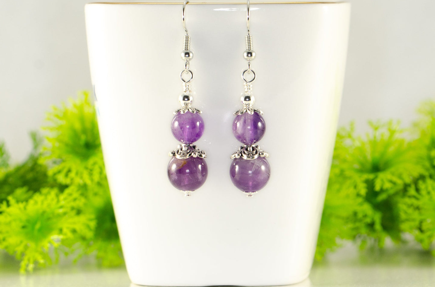 Natural Amethyst Dangle Earrings displayed on a tea cup.
