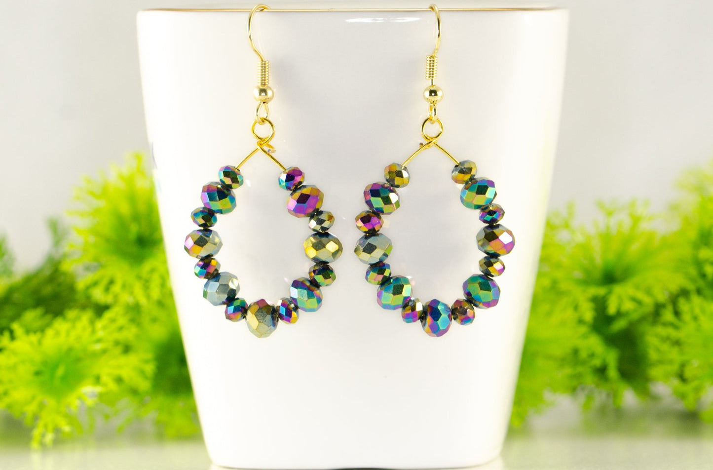 Sparkly Rainbow Glass Crystal Hoop Earrings displayed on a tea cup.