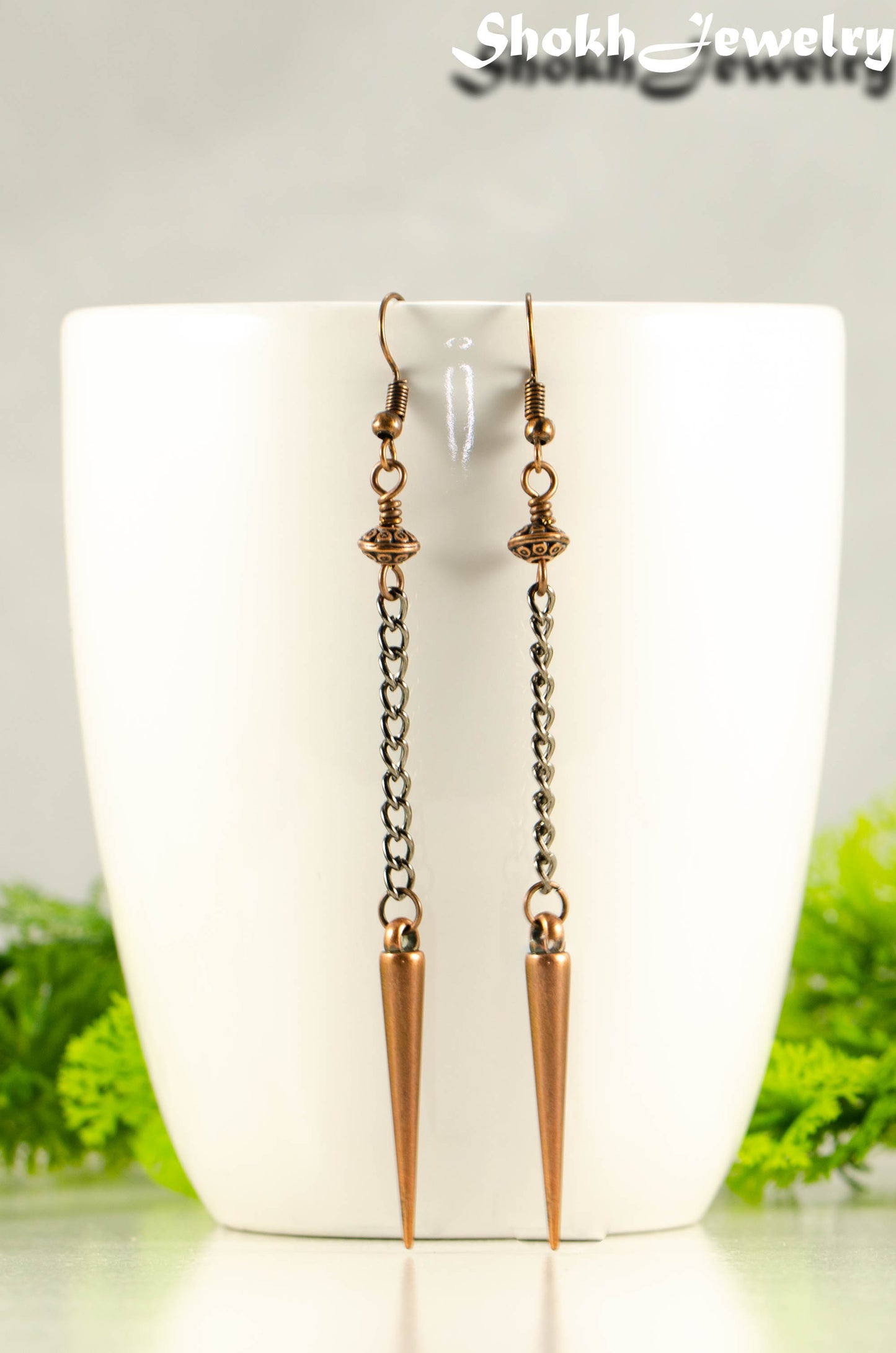 Statement chain and antique copper spike earrings on a mug