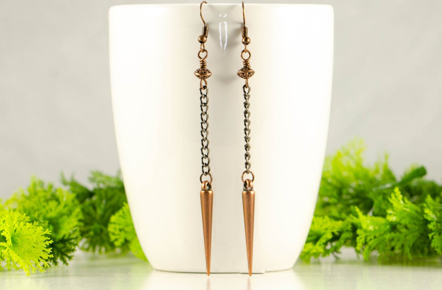 Statement chain and antique copper spike earrings on a mug