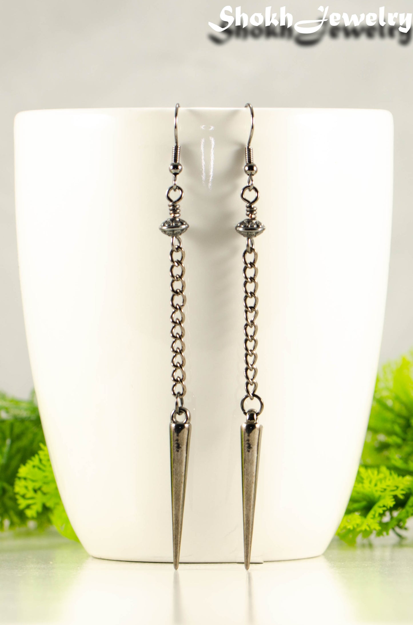 Statement chain and antique silver spike earrings on a mug