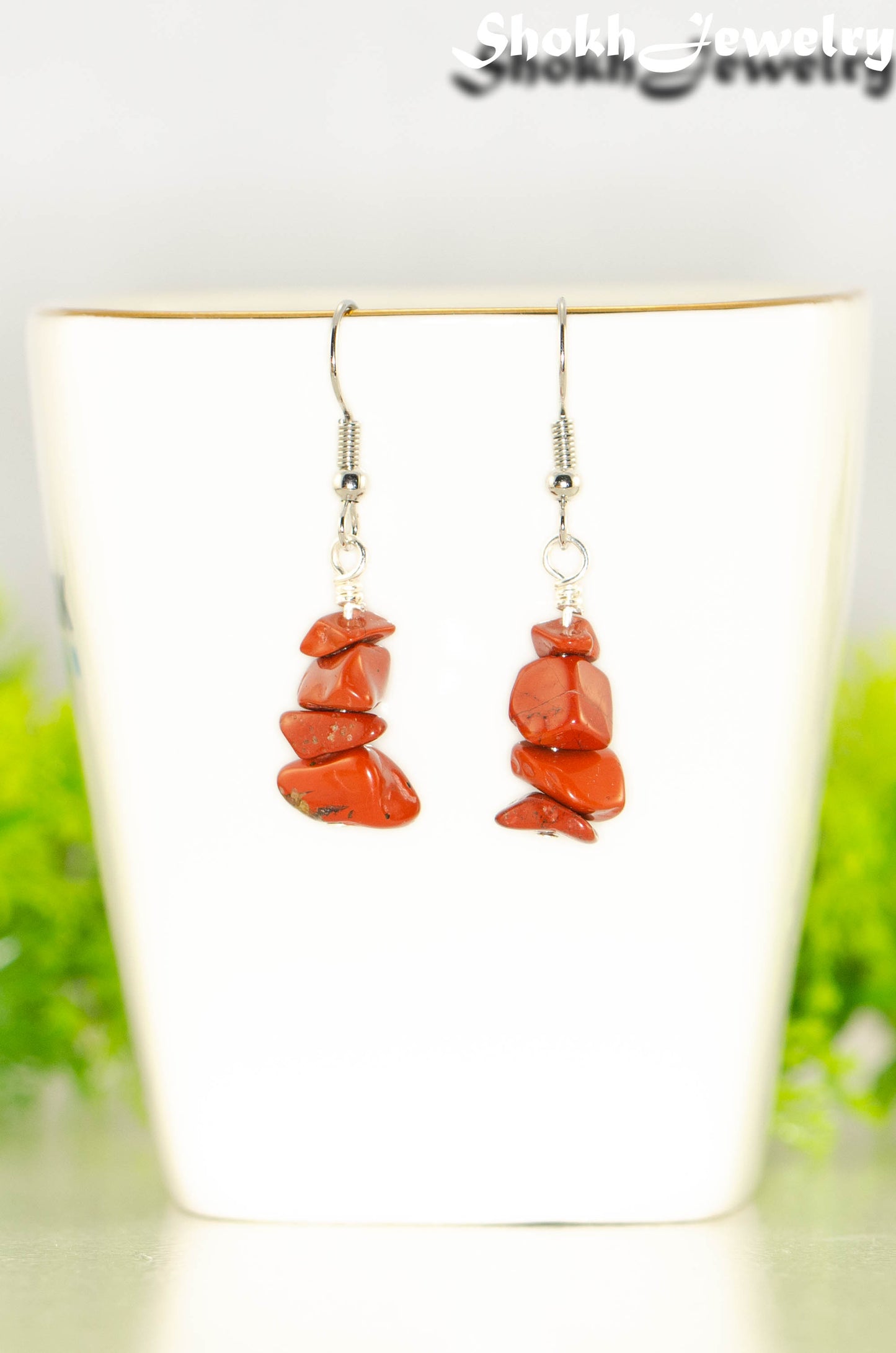 Simple Red Jasper Crystal Chip Earrings displayed on a tea cup.