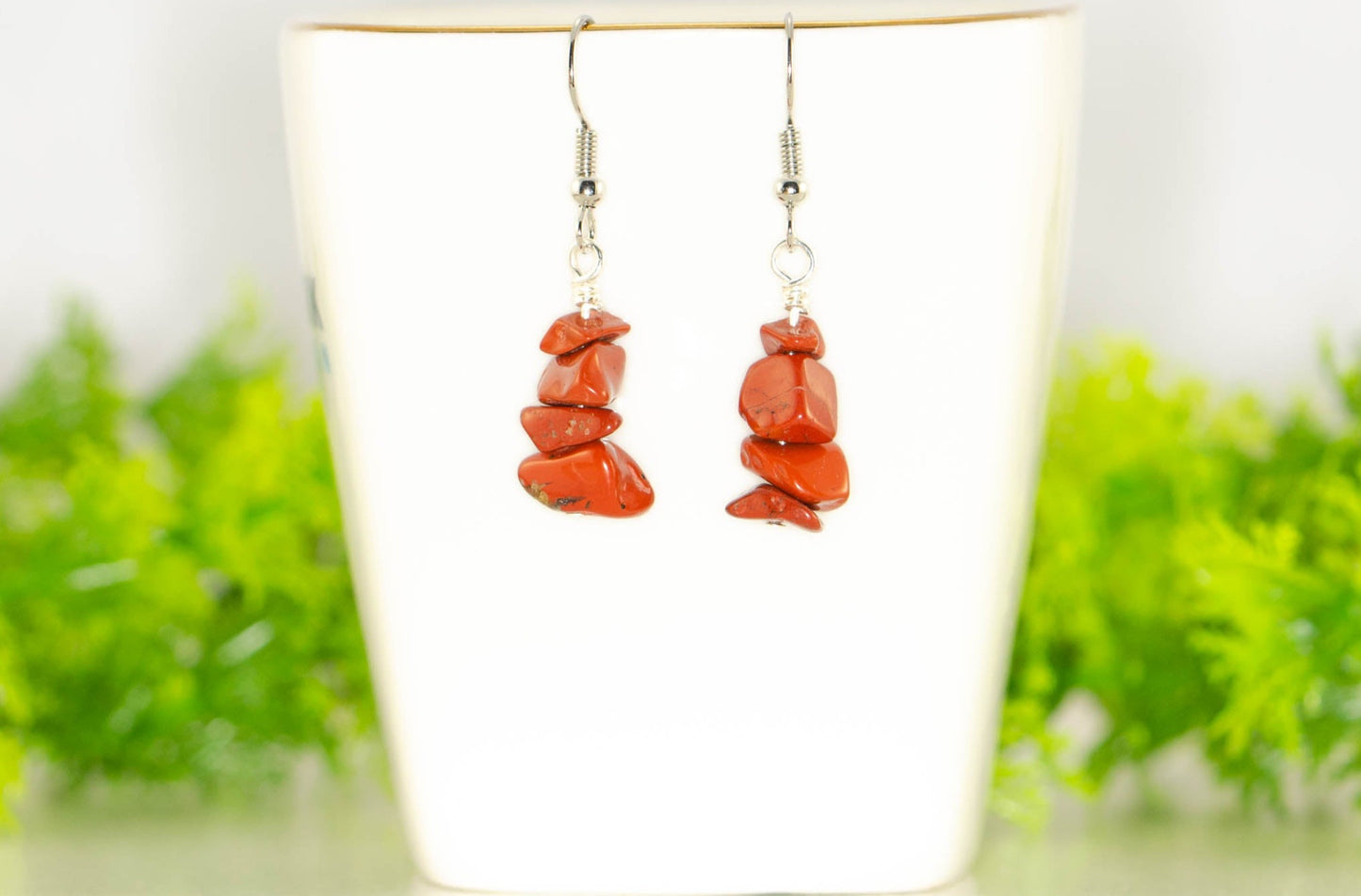 Simple Red Jasper Crystal Chip Earrings displayed on a tea cup.