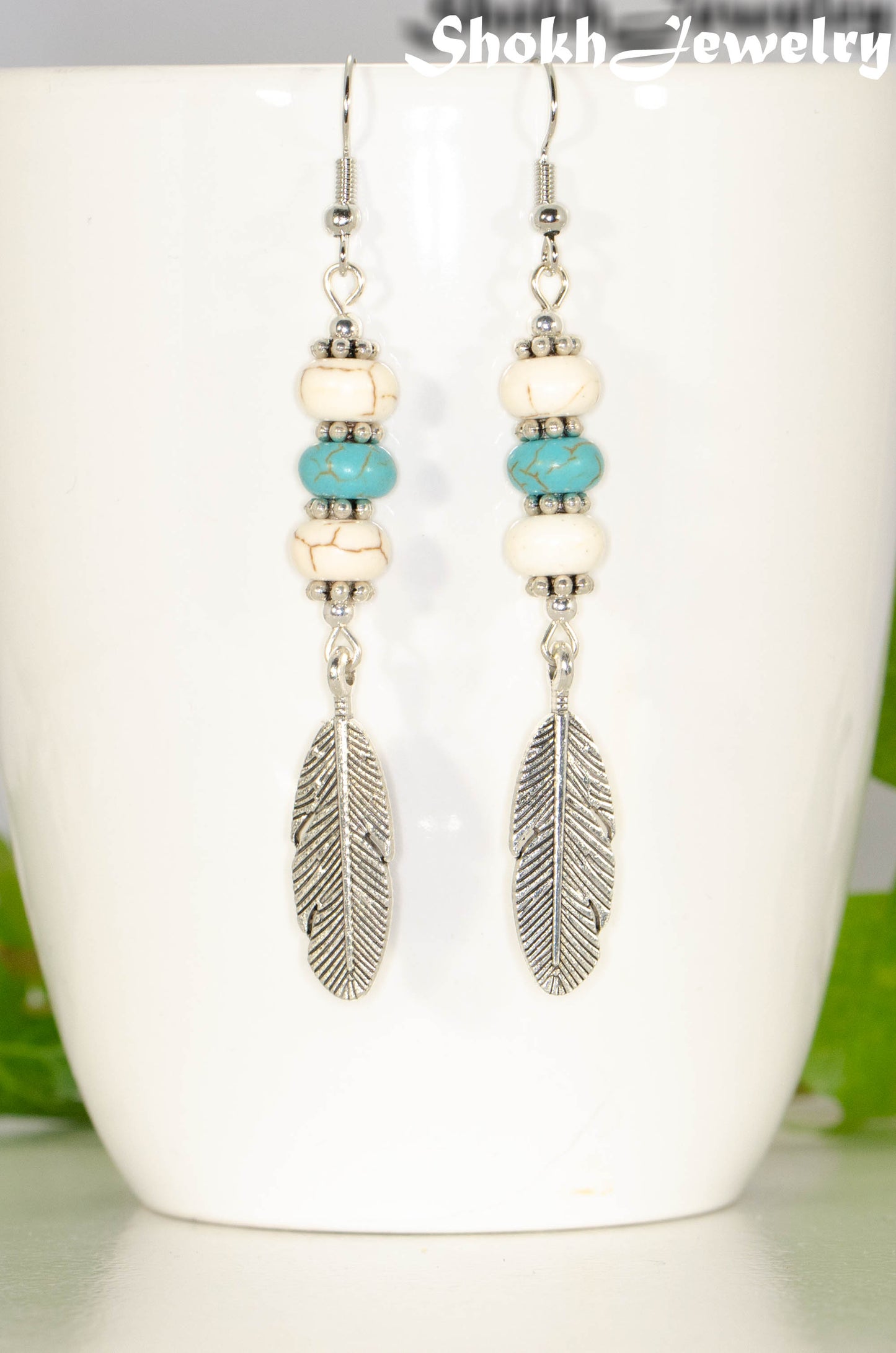 Close up of Statement White And Turquoise Howlite And Feather Earrings.