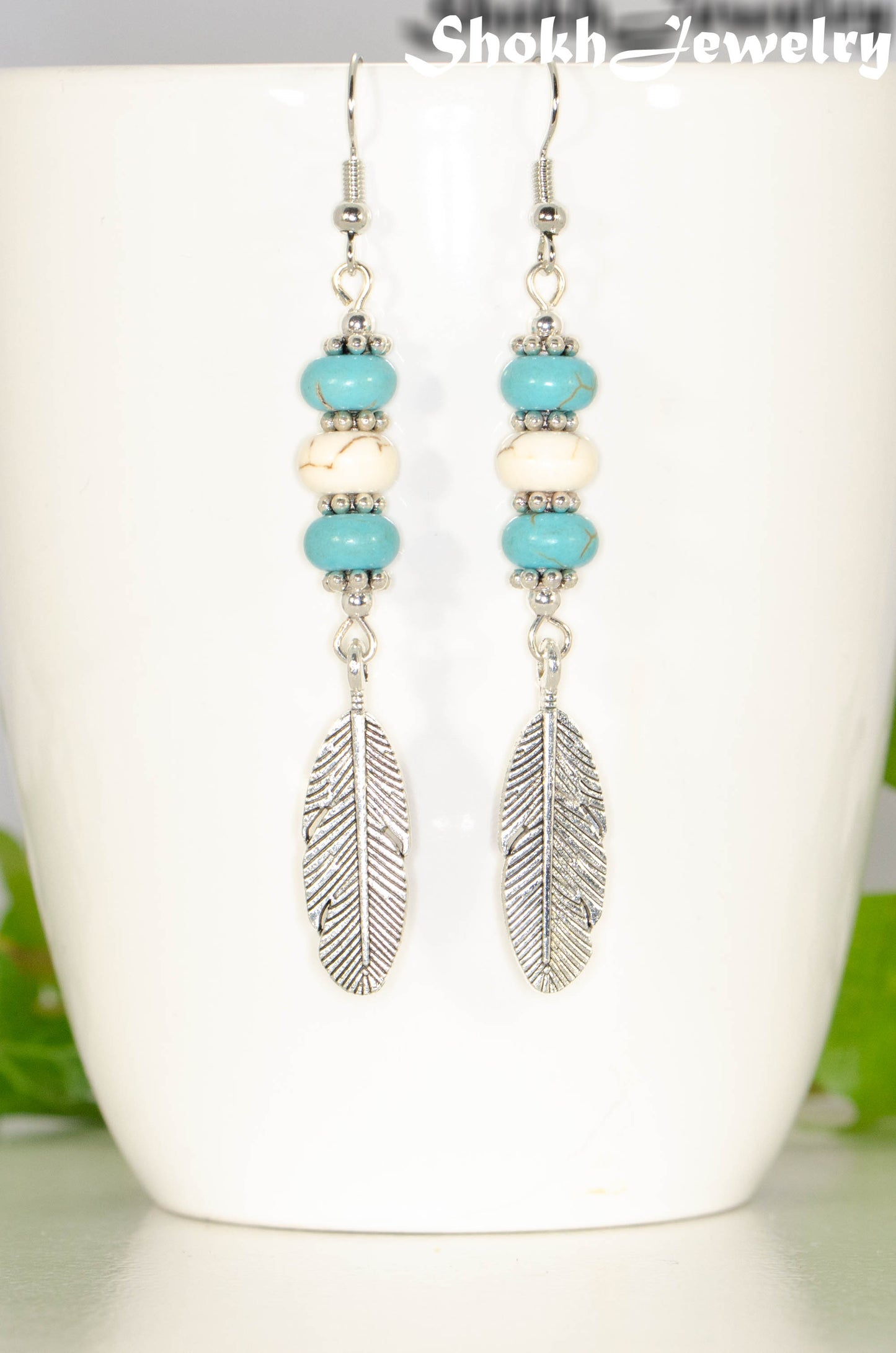 Close up of Statement Turquoise And White Howlite And Feather Earrings.