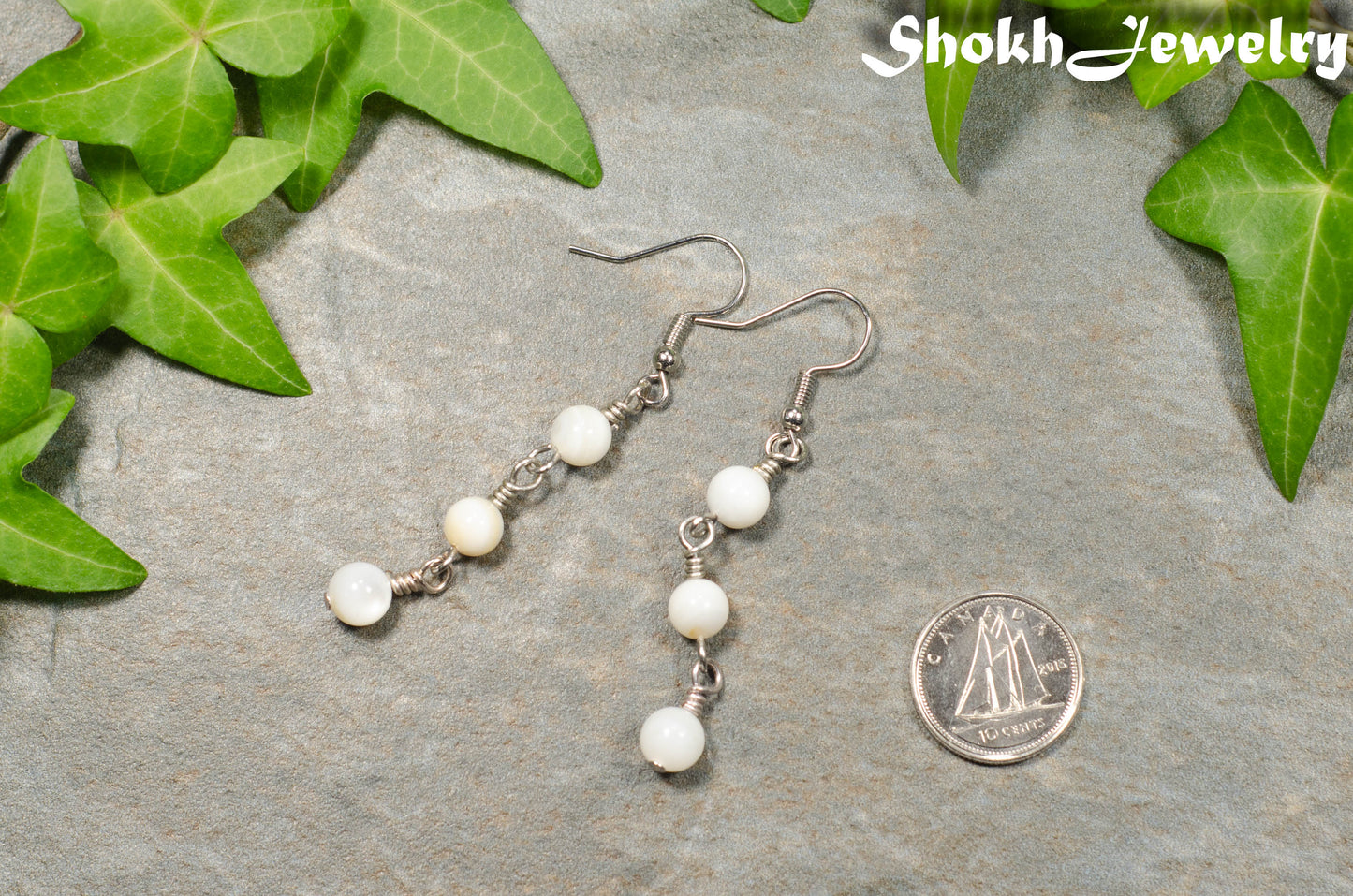 6mm White Natural Seashell Earrings beside a dime.
