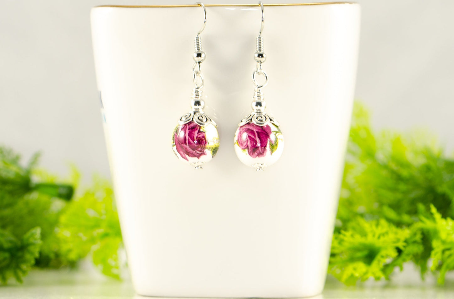 12mm Ceramic Pink Flower Earrings displayed on a tea cup