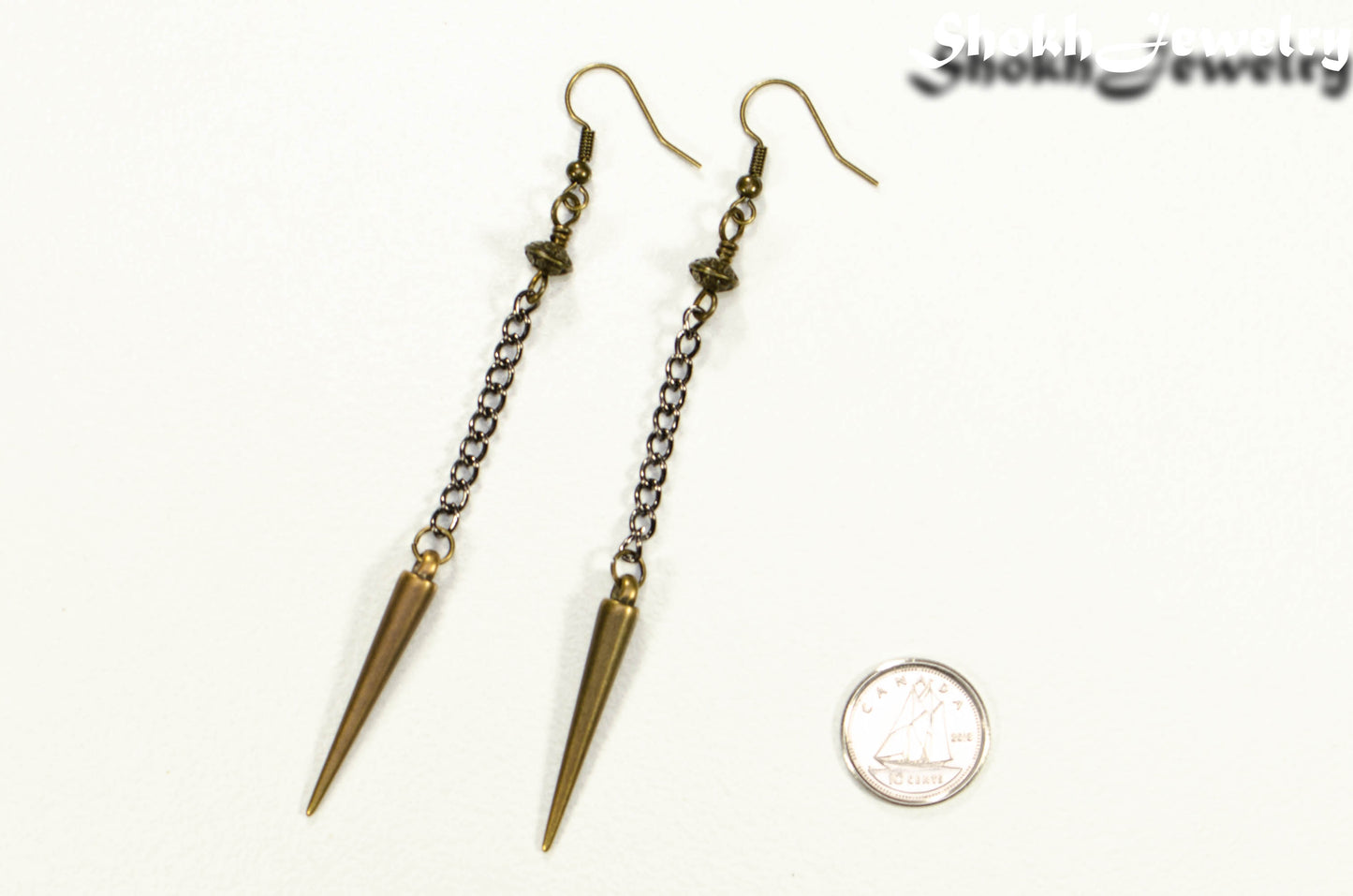 Statement chain and antique bronze spike earrings beside a dime