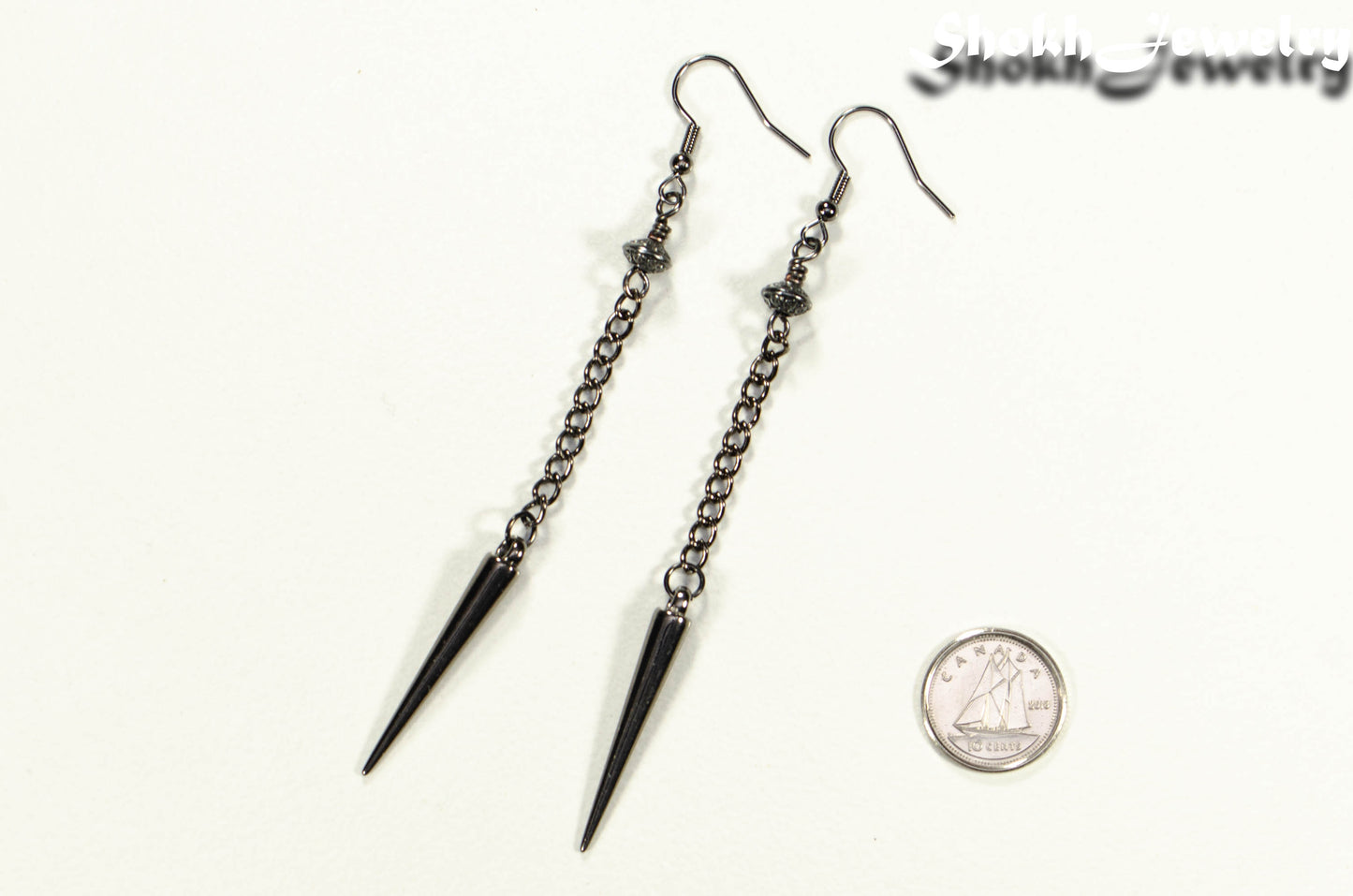 Statement chain and antique silver spike earrings beside a dime
