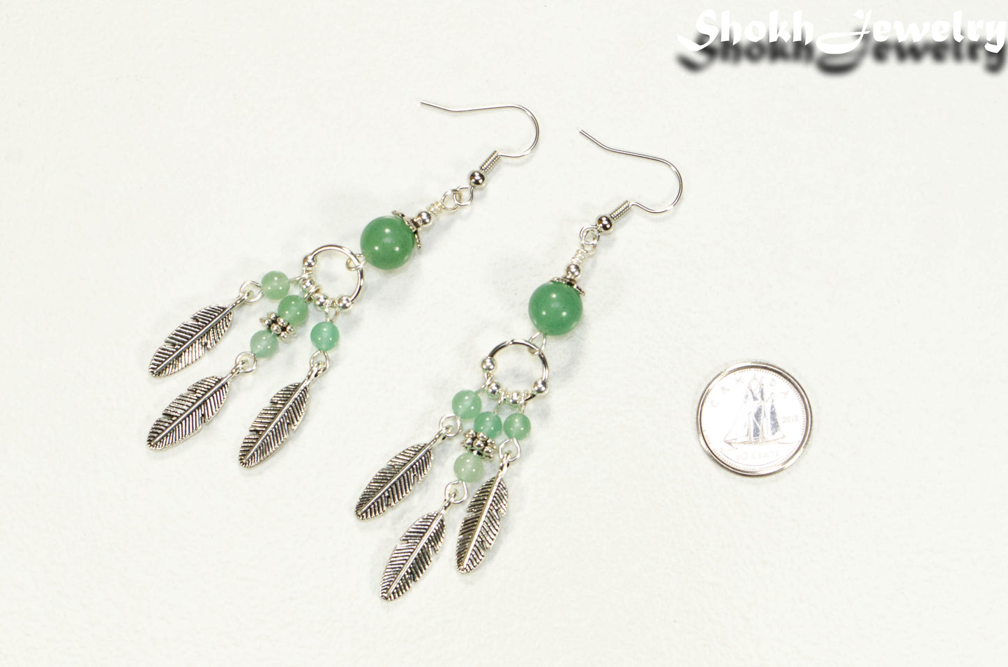 Statement Green Aventurine Crystal And Feather Earrings beside a dime.