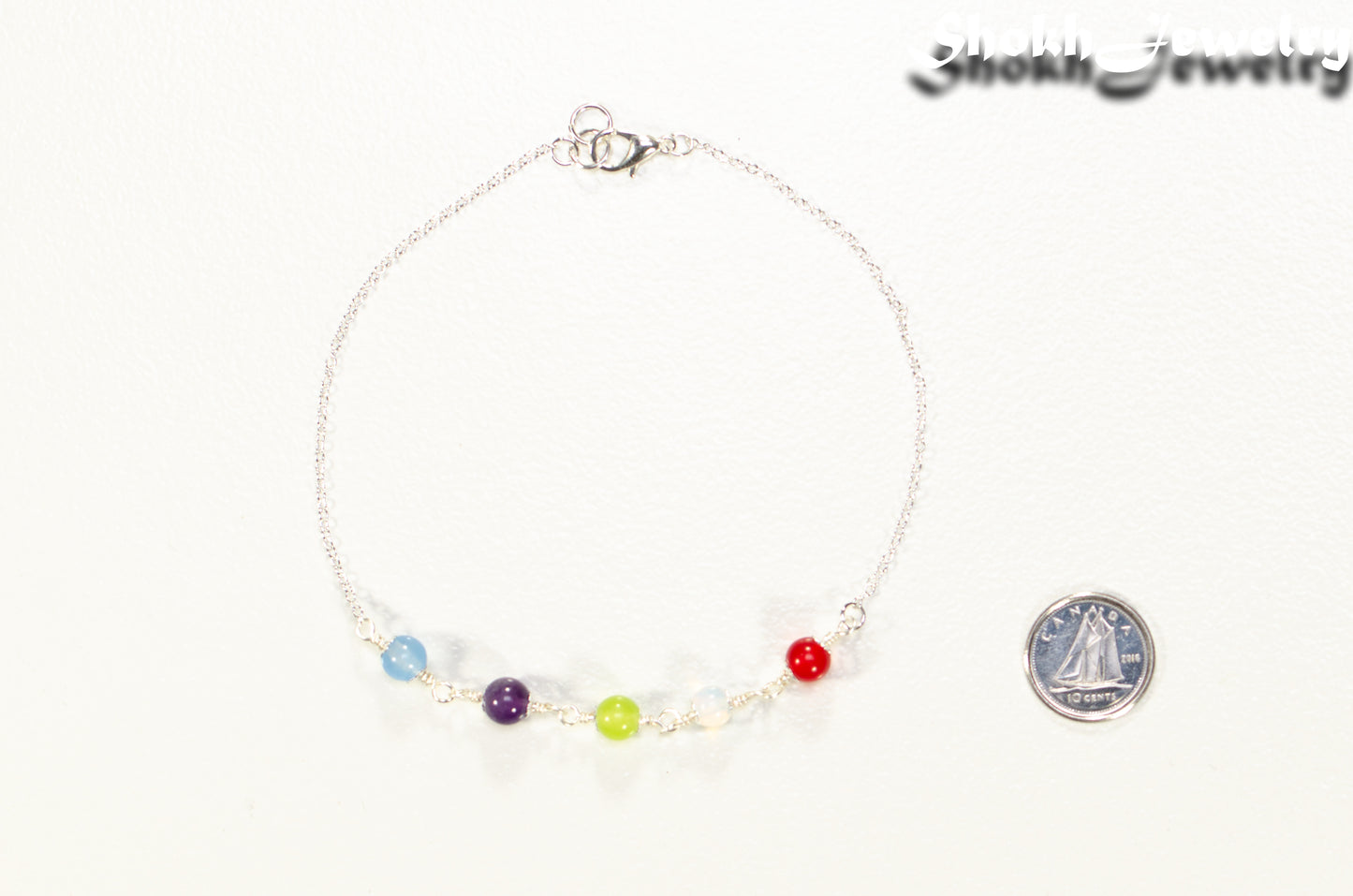 Custom Family Birthstone Bracelet with 5 birthstones beside a dime.