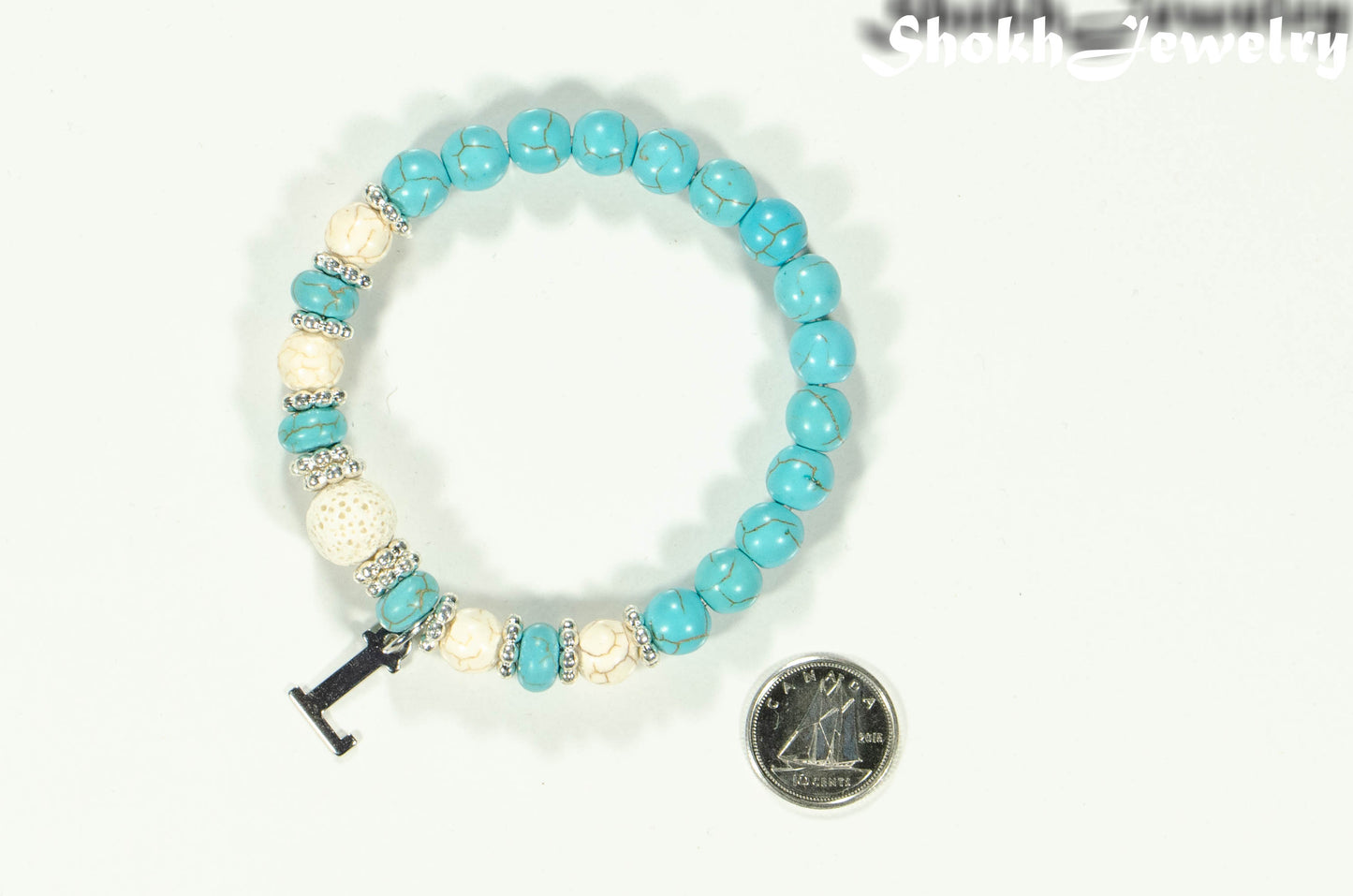 Turquoise Howlite and Lava Stone Bracelet with Initial beside a dime.