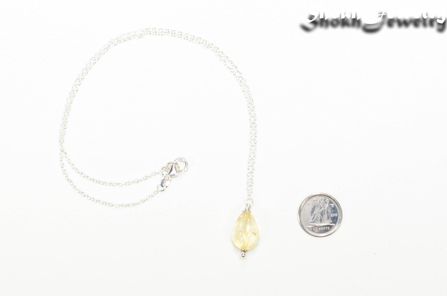 Dainty Citrine Nugget Pendant Necklace beside a dime