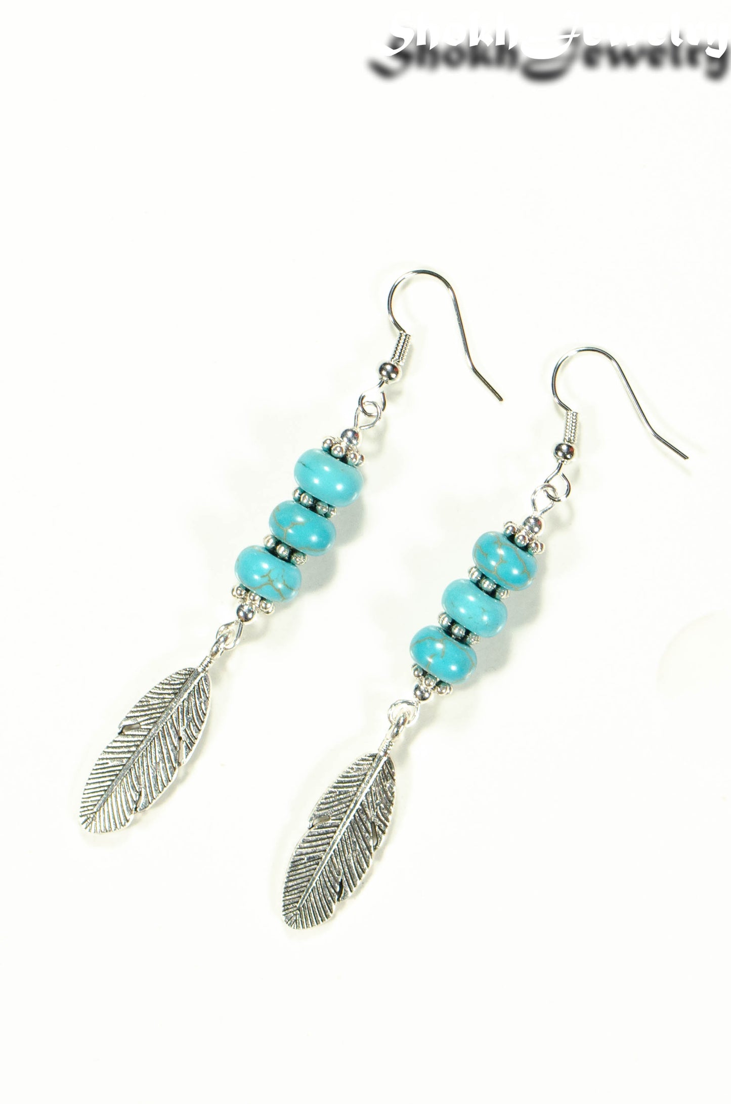 Top view of Statement Tibetan Silver Feather And Turquoise Howlite Earrings.