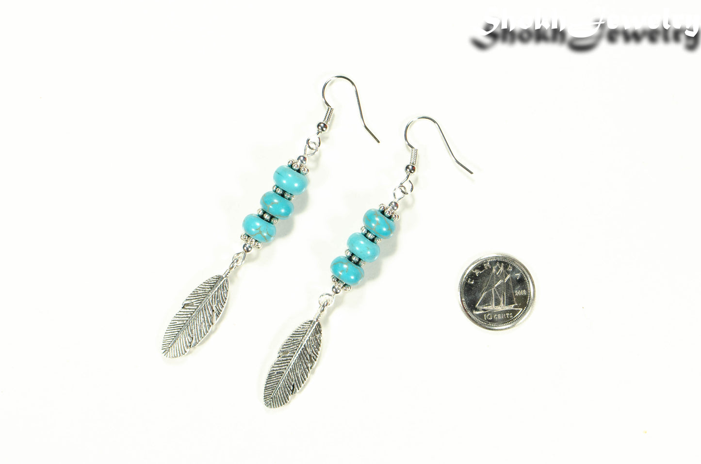 Statement Tibetan Silver Feather And Turquoise Howlite Earrings beside a dime.