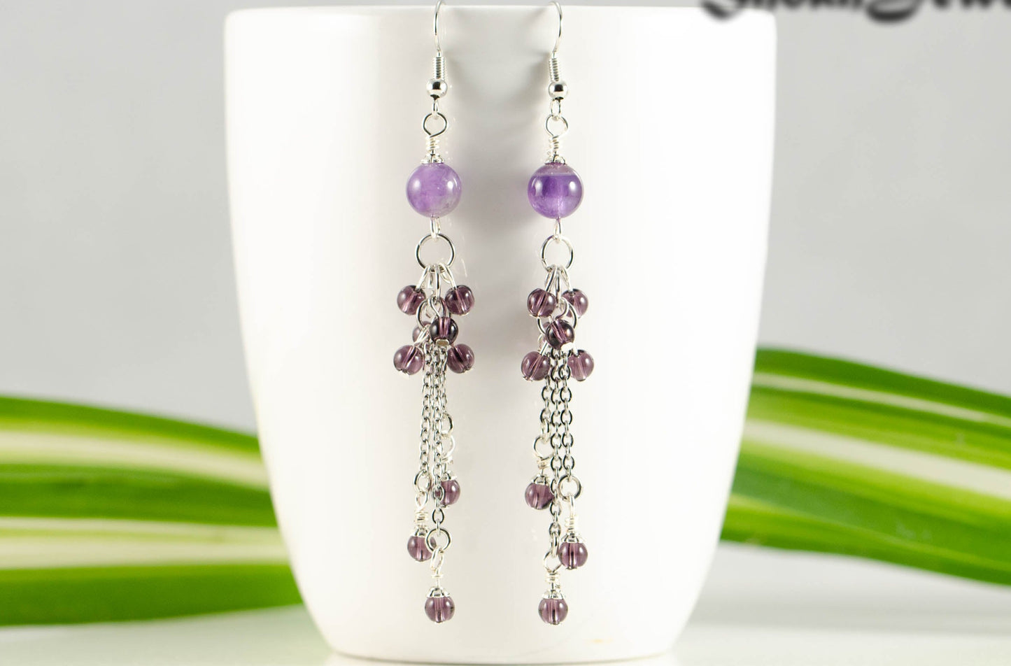 Long Stainless Steel Chain and Amethyst Earrings displayed on a coffee mug.