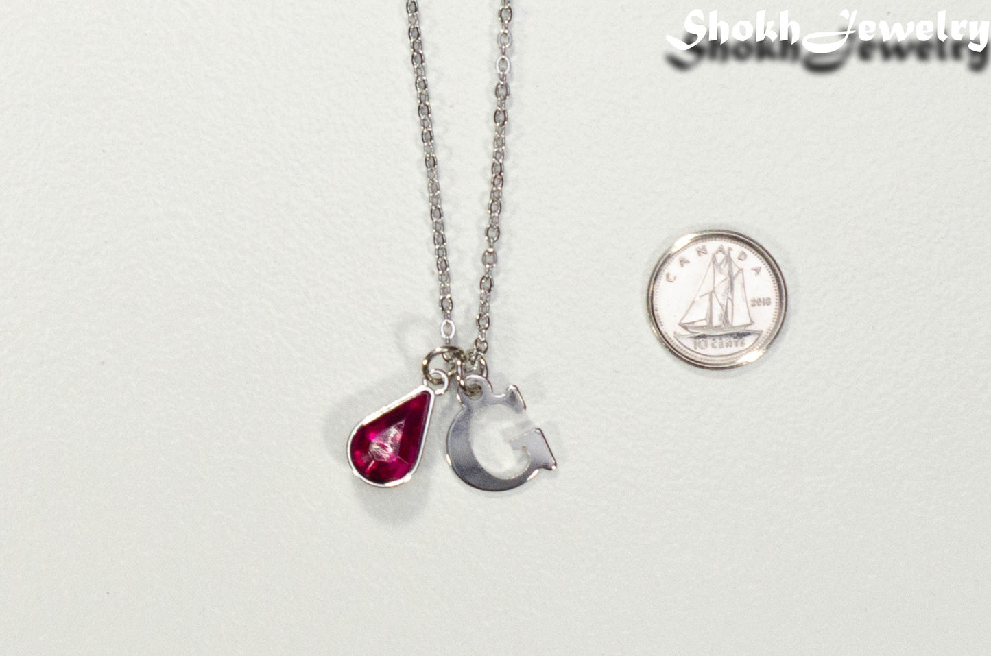 Personalized October Birthstone pendant beside a dime