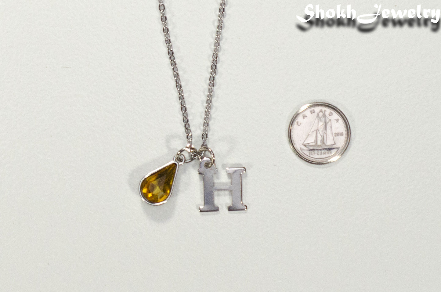 Personalized November Birthstone pendant beside a dime