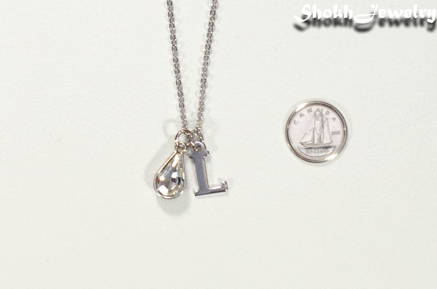 Personalized April Birthstone pendant beside a dime