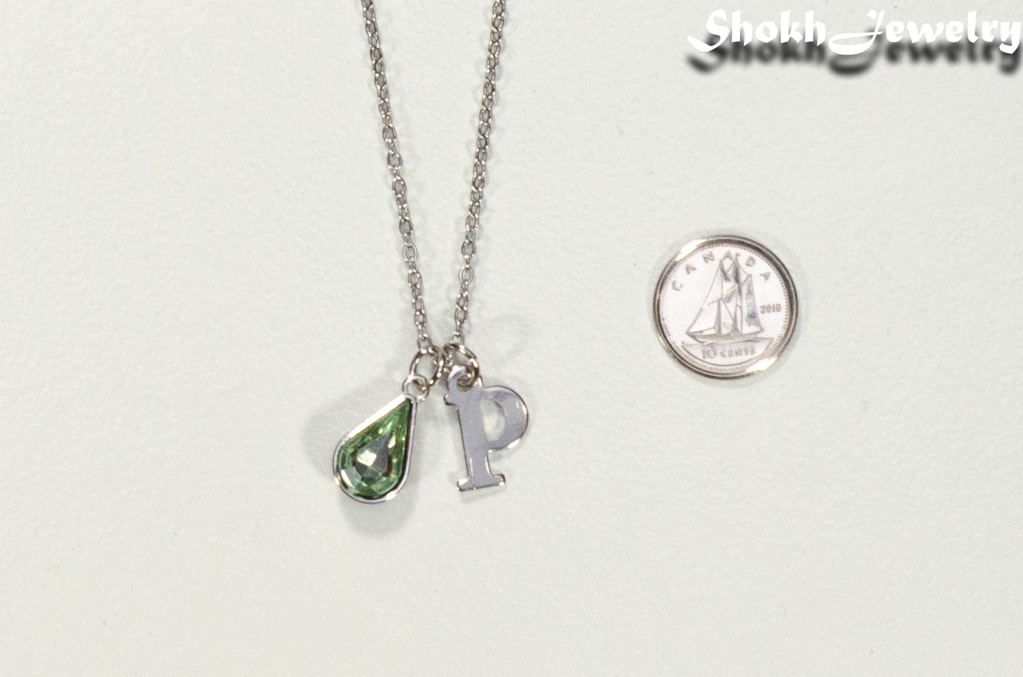 Personalized August Birthstone pendant beside a dime