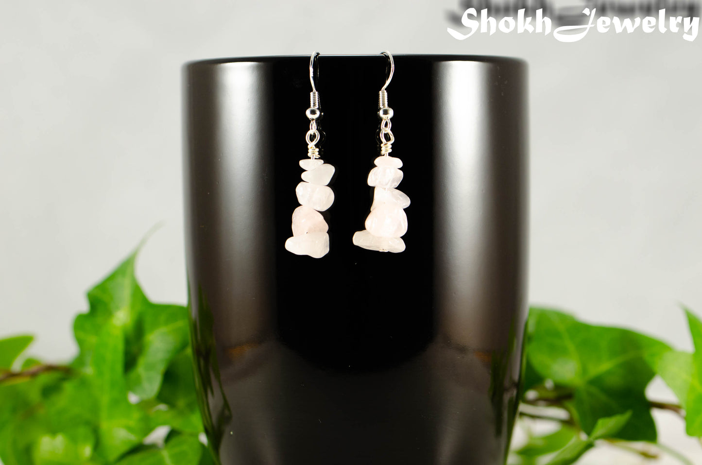 Simple Rose Quartz Crystal Chip Earrings displayed on a coffee mug.
