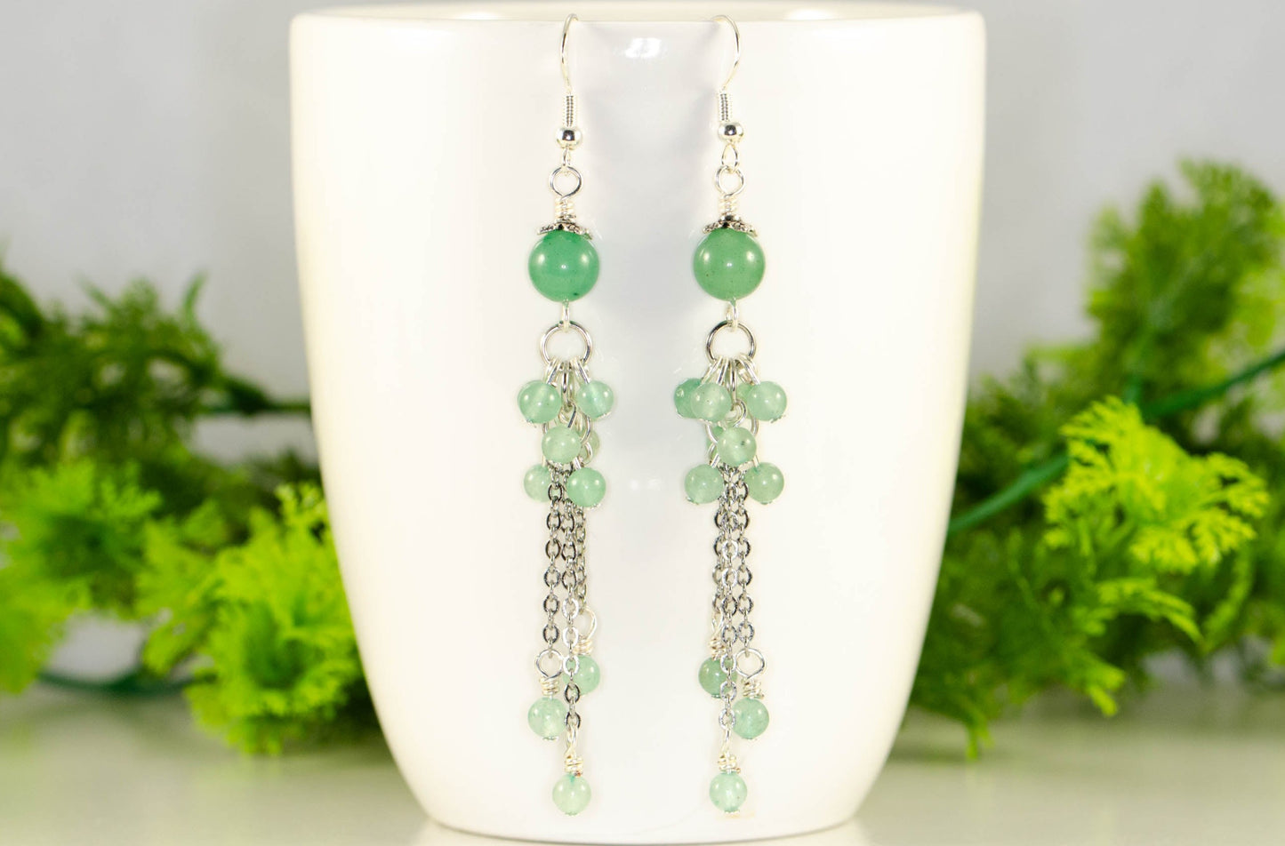 Long Stainless Steel Chain and Green Aventurine Earrings displayed on a coffee mug.
