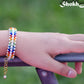 Rainbow seed bead and pearl woven bracelet on a wrist.