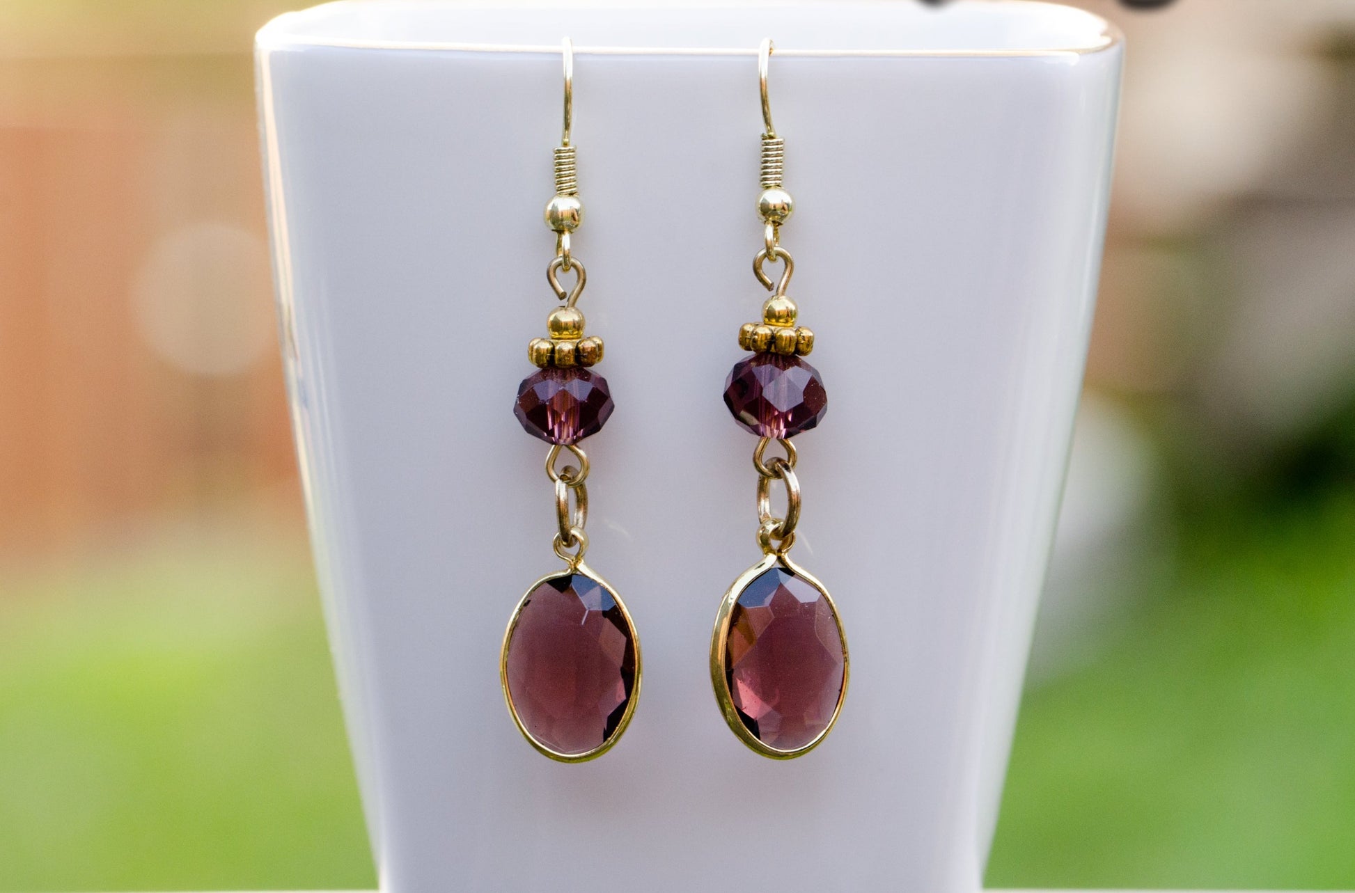 Brown Oval Glass Dangle Earrings displayed on a tea cup.