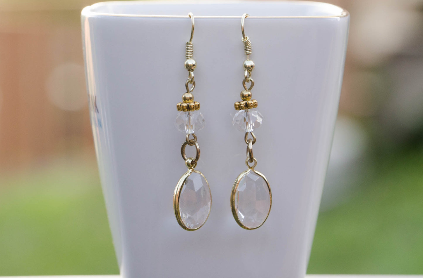 Clear Oval Glass Dangle Earrings displayed on a tea cup.