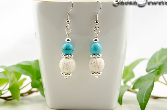 Turquoise Howlite and White Lava Rock Earrings displayed on a tea cup.