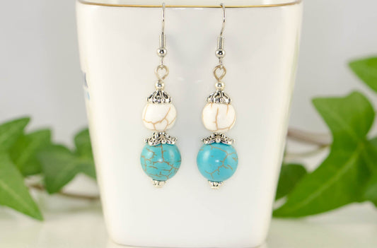 Turquoise and White Howlite Dangle Earrings displayed on a tea cup.
