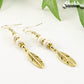 Close up of Statement White Howlite And Gold Feather Earrings.