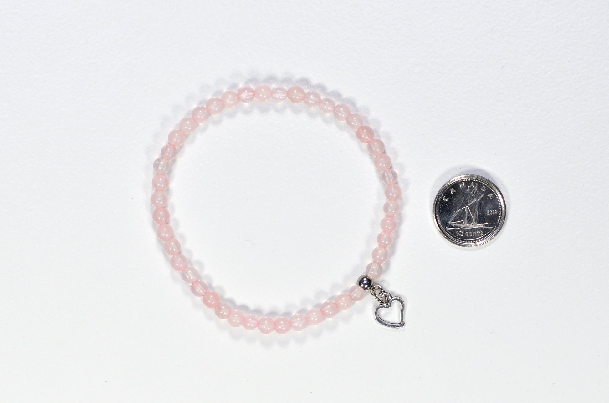 4mm Rose Quartz Bracelet with Heart Charm beside a dime.