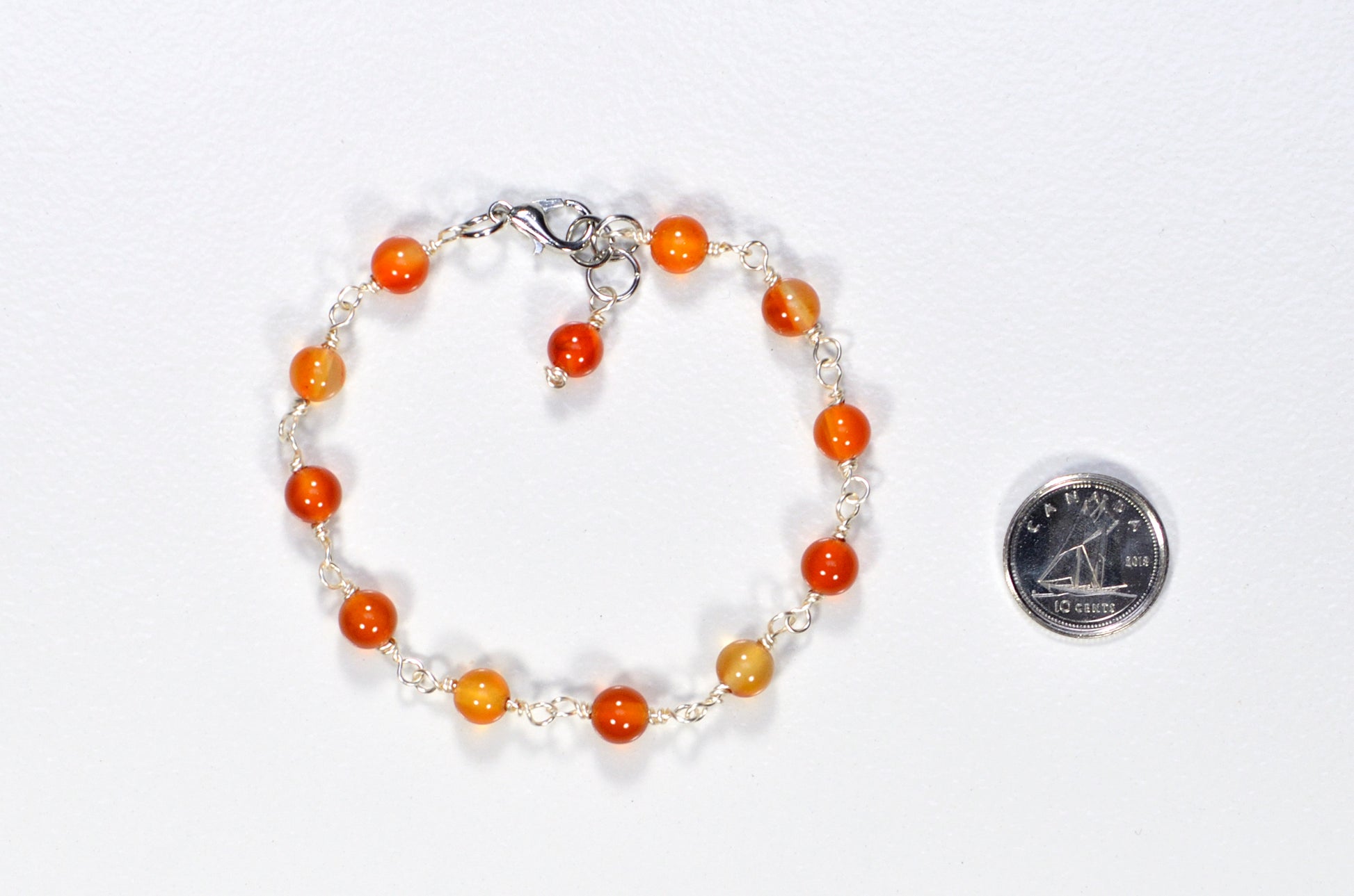 6mm Carnelian Link Bracelet for Women beside a dime.