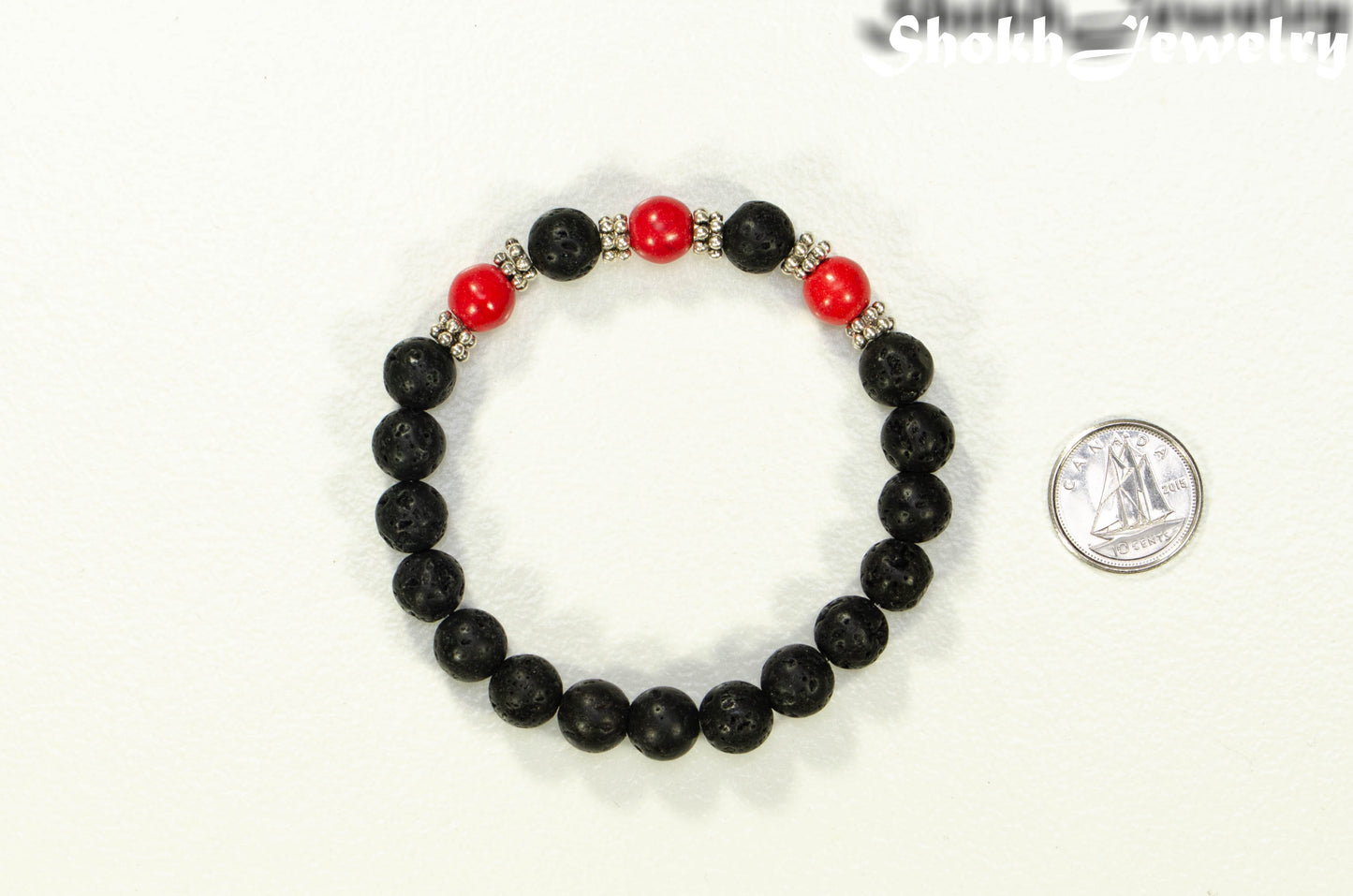 8mm Black Lava Stone and Red Howlite Bracelet beside a dime.