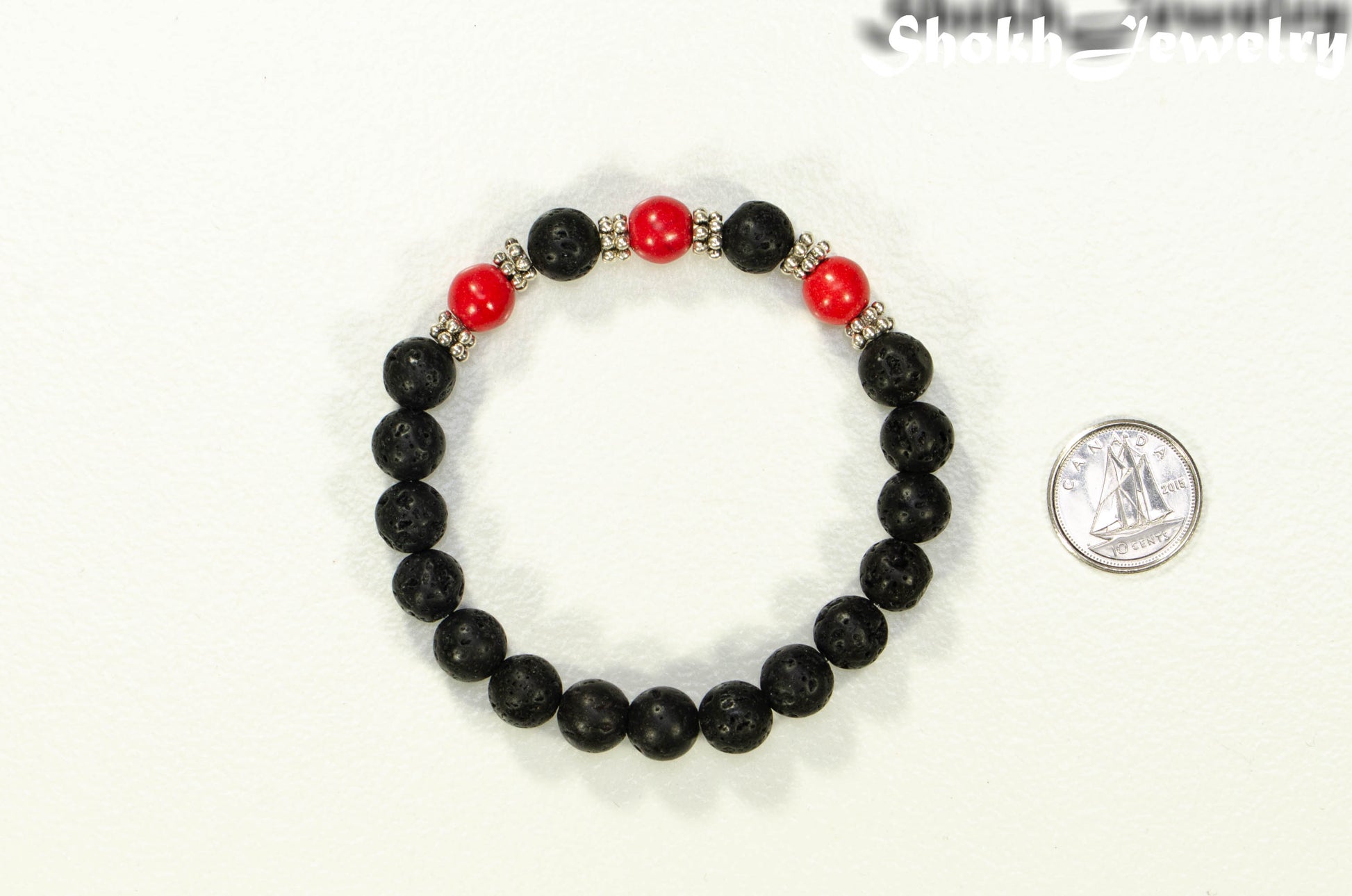 8mm Black Lava Stone and Red Howlite Bracelet beside a dime.