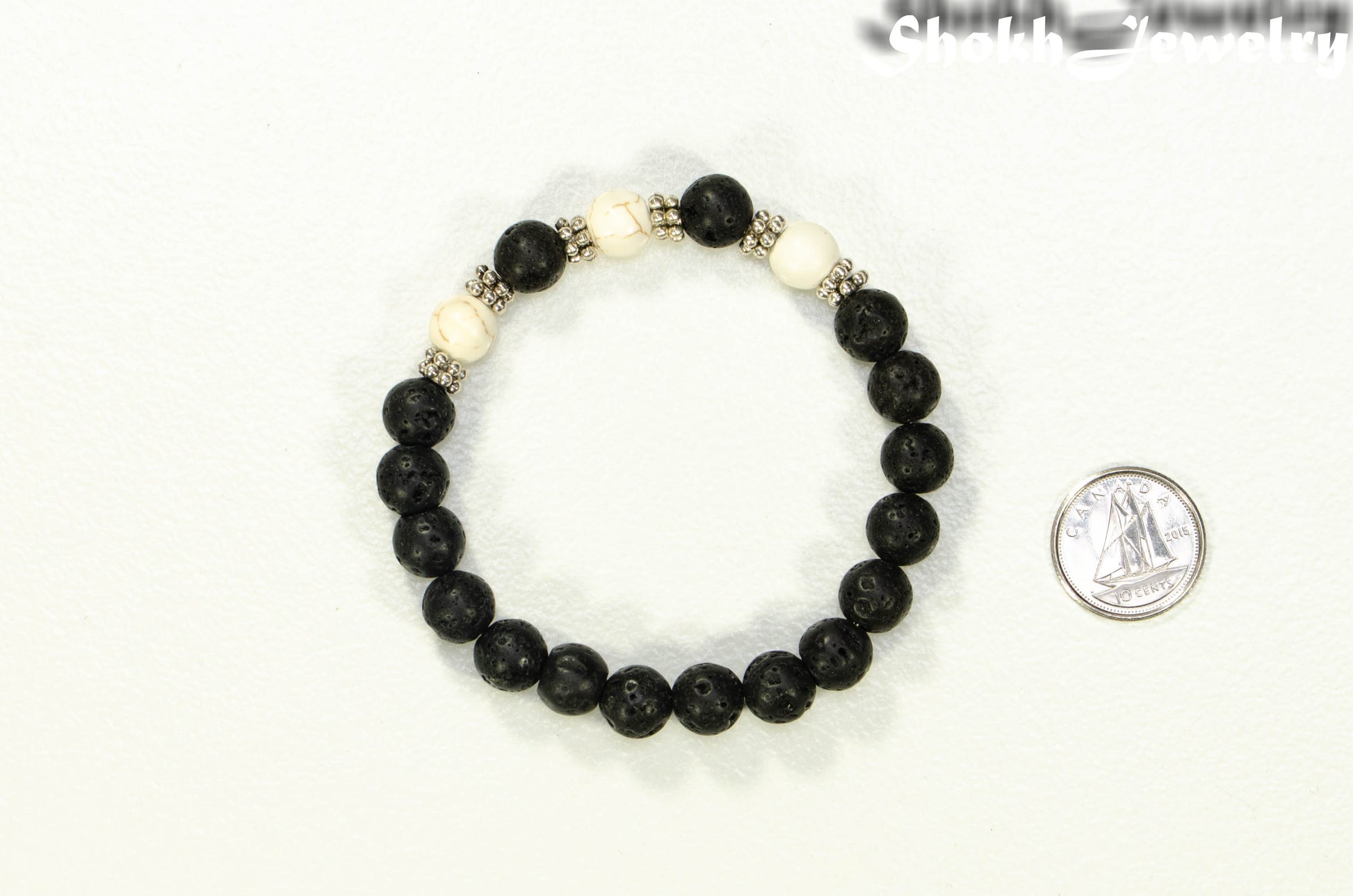 8mm Black Lava Stone and White Howlite Bracelet beside a dime.
