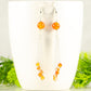 Cascading Carnelian Crystal Drop Earrings displayed on a coffee mug.