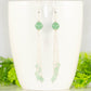 Cascading Green Aventurine Crystal Drop Earrings displayed on a coffee mug.