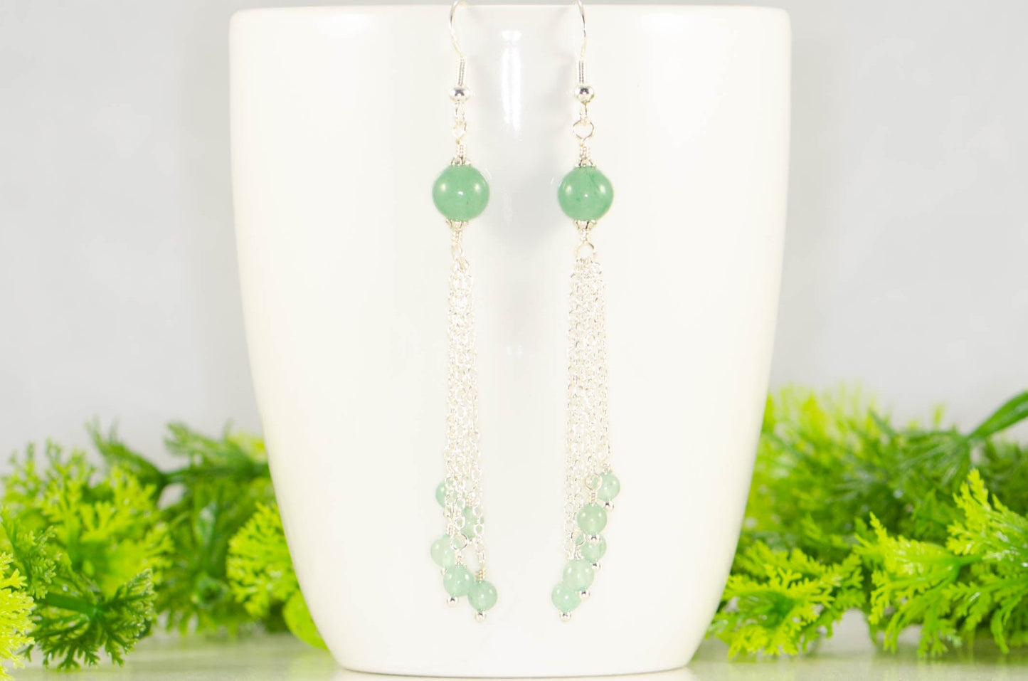 Cascading Green Aventurine Crystal Drop Earrings displayed on a coffee mug.