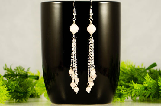 Cascading Rose Quartz Crystal Drop Earrings displayed on a coffee mug.