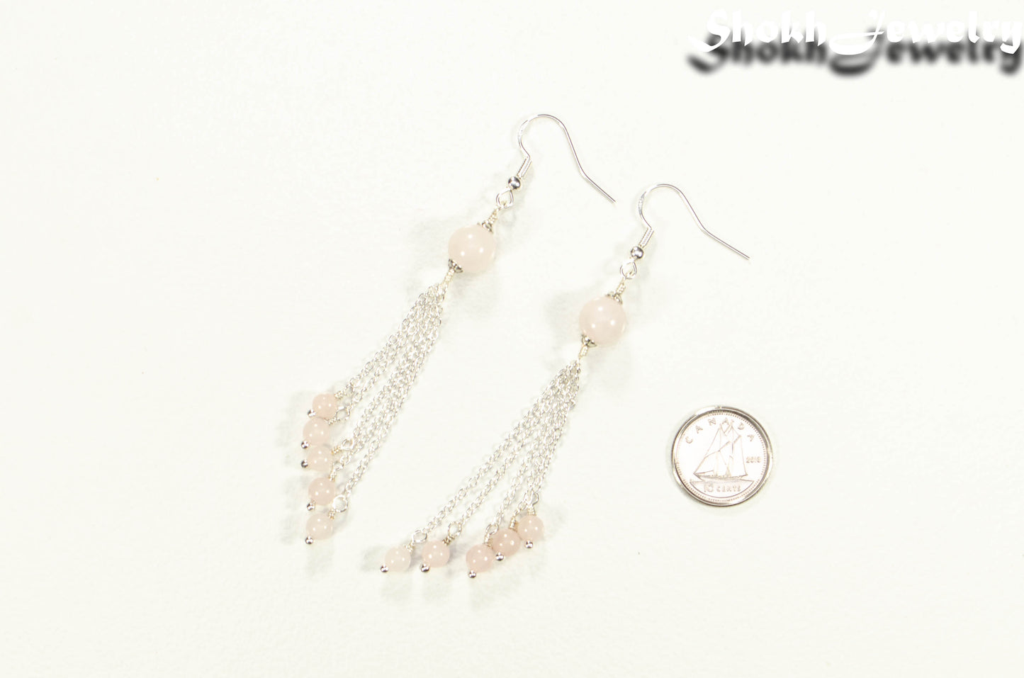 Cascading Rose Quartz Crystal Drop Earrings beside a dime.
