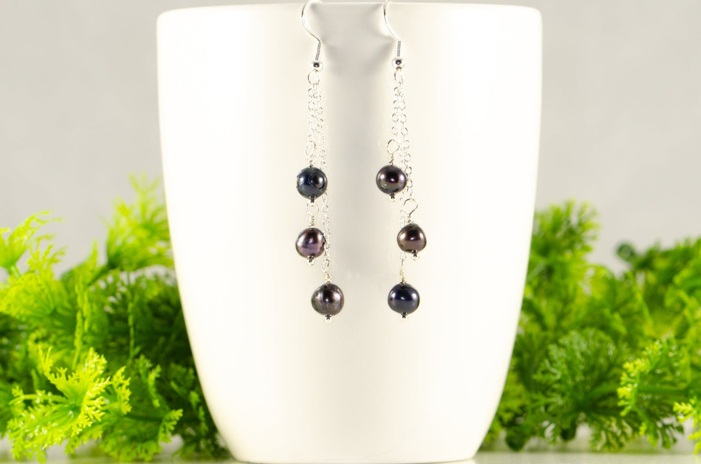 Long Silver Plated Chain and Black Pearl Earrings displayed on a coffee mug.