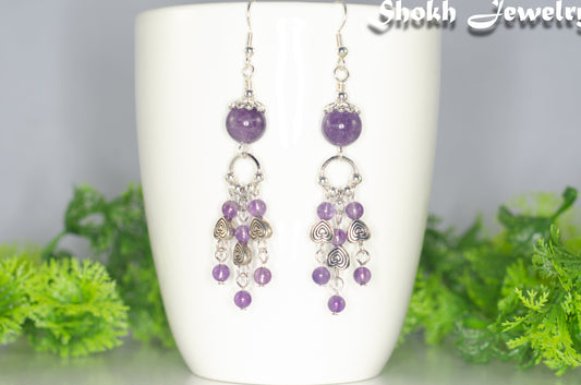Natural Amethyst and Heart Chandelier Earrings displayed on a white mug.