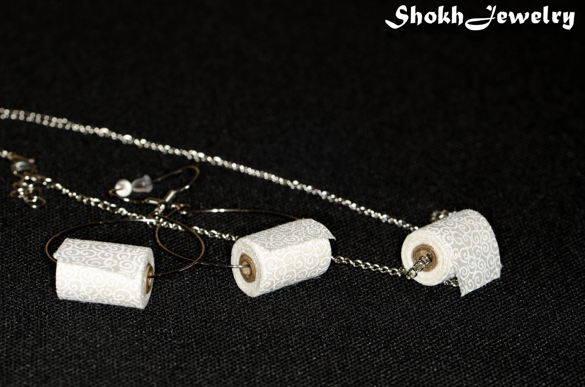 Close up of Miniature Toilet Paper Roll Necklace and Earrings Set.