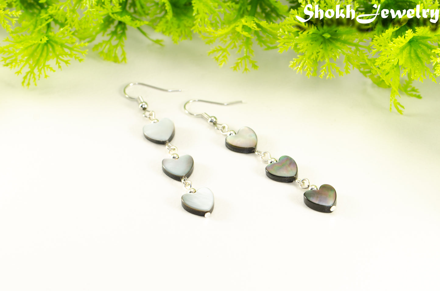Close up of Long Grey Seashell Hearts Earrings.