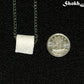 Tiny Toilet Paper Roll Necklace beside a dime.